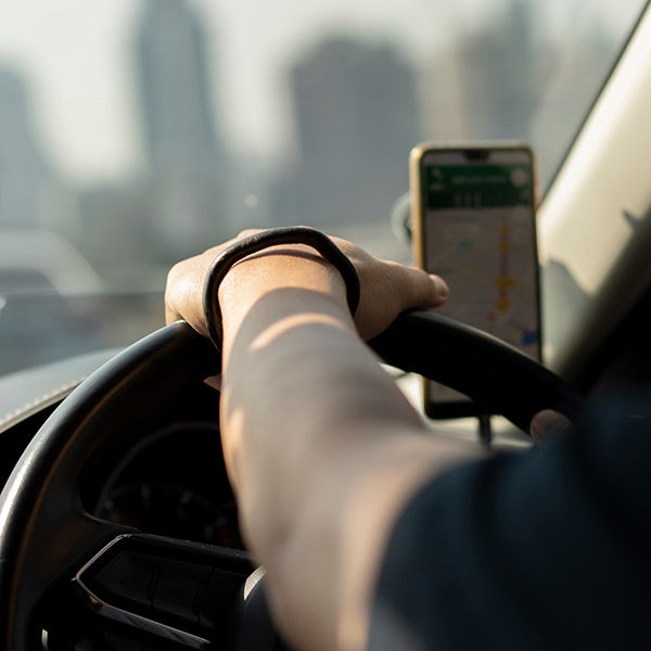 A person is driving a car while holding a cell phone.