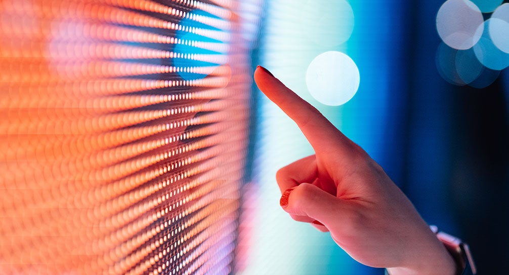 A woman's finger is pointing at a colorful screen.
