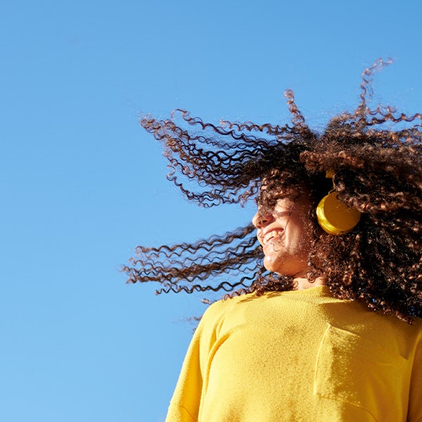 A young woman with curly hair is wearing earphones.