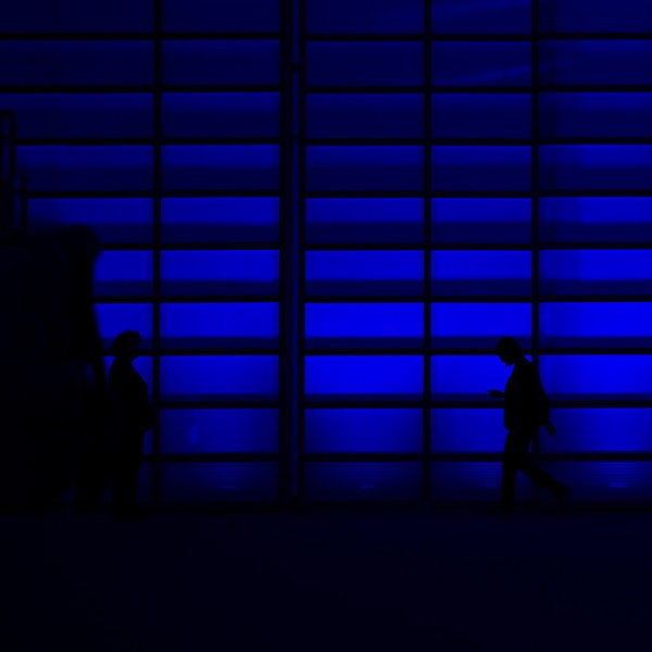 Two people walking in front of a blue glass door.